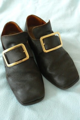 Black leather shoes with gold coloured buckle.