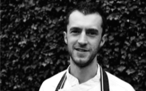 Black and white head and shoulders photo of man wearing chef's whites. © The Wheatsheaf Pub & Grill