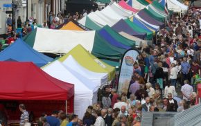 Aerial view of people and colourful market stalls at Food Festival held in street.
