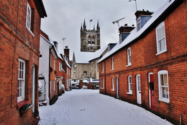 Snow, houses on left and right. Church tower in background.