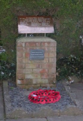 War memorial on a brick plinth. Poppy wreath at base.