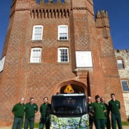 group of males next to a floral van, red brick castle behind.