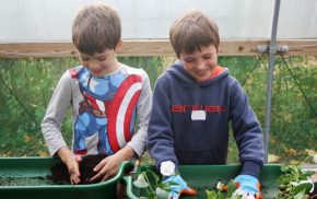 Two boys planting up plants at a gardening workshop.