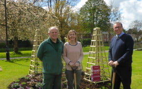 Two males and one female standing in front of flower bed