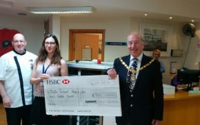 Two males and a female with holding a large cheque.