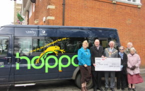 People in front of bus receiving a cheque.