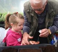 Male and child planting seeds at gardening workshop.