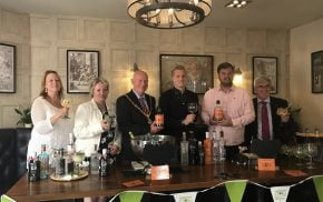 Mayor and group of people holding gin glasses.