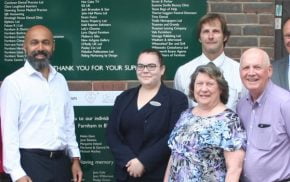 Group of people in front of a green sign.