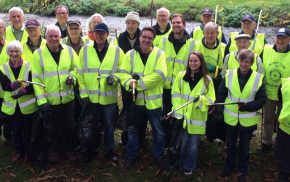 Group of litter pickers in high viz jackets and holding bags and litter picks