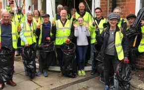 Group of people in high visibility jackets holding litter pickers and black sacks