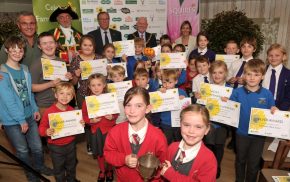 Group of children holding certificates and a trophy.