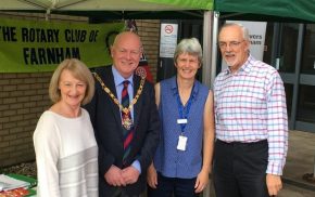 Four people (including the Mayor) standing in front of two green gazebos at a health and well-being event.