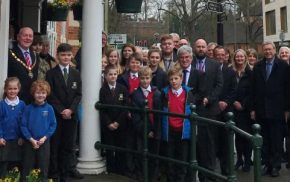 Group of students and adults outside a red brick building.