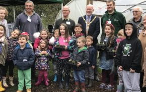 Group of children and adults outside a poly tunnel.