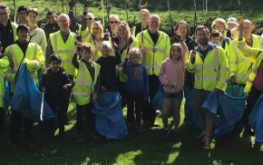 People in high viz jackets holding blue sacks and litter pickers.