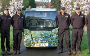 Group eight males standing next to a vehicle with flowery livery.