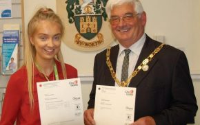 Young girl holding a certificate with the Mayor on her left.