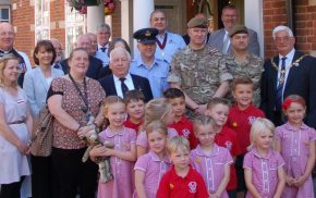 Group of children with soldiers and adults.