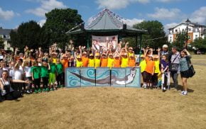 Large group children standing behind a painting of an otter.