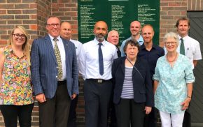 Group of people standing in front of a sign.