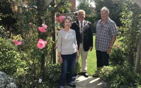 Female, Mayor and male stand under an archway in a pretty garden.