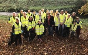 People in high viz jackets holding black sacks and litter pickers.