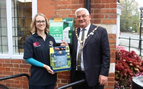 Female and Mayor holding a defibrillator in a box