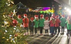 Back of children on stage. Christmas tree.