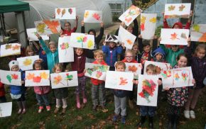 Children holding paintings of leaves.