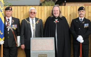 Mayor, men in uniform and vicar at a war memorial.