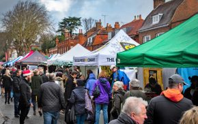 Crowd of people at an outdoor market. Colourful gazebos in street