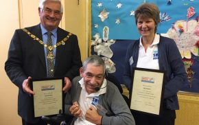 Man in wheelchair with the Mayor and a female holding certificates.