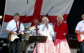 Band singing and playing on a stage.