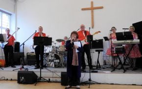 Female on microphone. Band behind her on a stage.