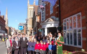 Group of adults and schoolchildren in front of red brick building