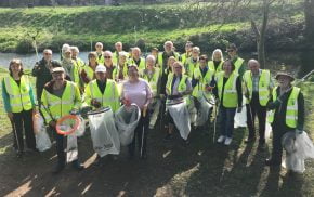 Group of people in high viz jackets holding sacks and litter picks