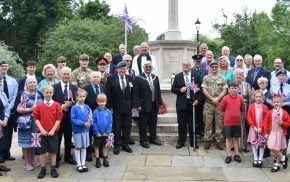 Group of adults and children standing in front of war memorial