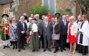 Mayor with group of people in smart clothes standing outside church.