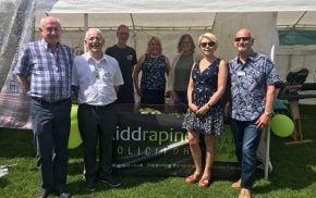 Group of people standing in front of a small marquee.