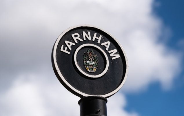 Black circular sign post with Farnham painted in white letters around top of circle