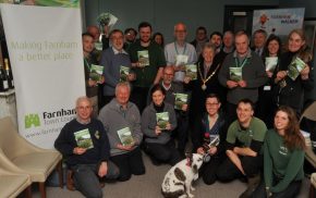 Group of people holding a booklet. Dog in foreground