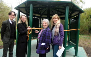 Four people with one cutting a ribbon across entrance to shelter