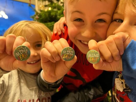 3 children holding up a badge