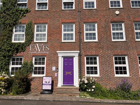 Photo of a large brick building with symmetrical windows and a purple door