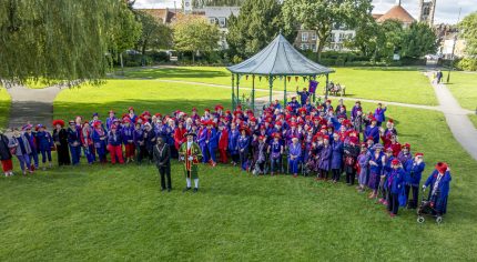 Large group of ladies dressed in purple clothes and red hats.