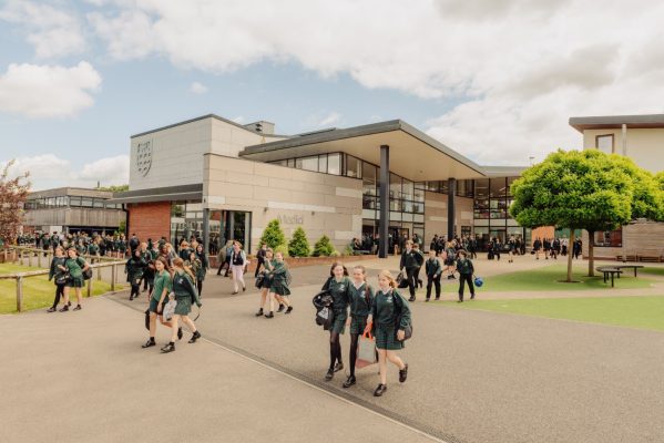 Exterior of a modern school building with school children walking about