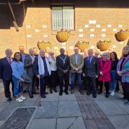 Group of people gathered in front of wall mounted with plaques.