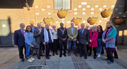 Group of people gathered in front of wall mounted with plaques.