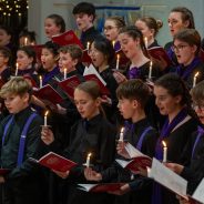 Young people singing by candlelight in a choir.